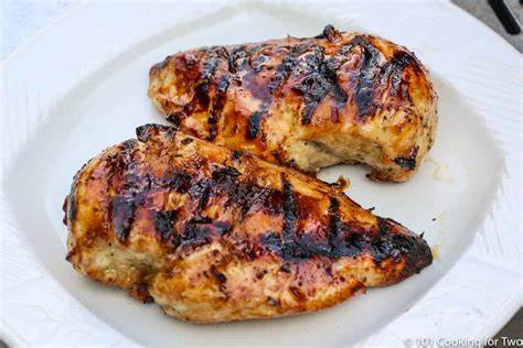 Two grilled chicken breasts on a plate.